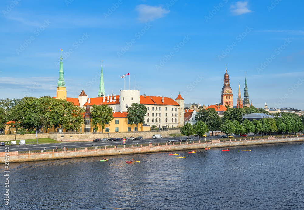 Obraz premium Riga, Latvia - August 23, 2017: Beautiful early morning cityscape of the old town of Riga, St Peter's Church Tower and Daugava river, Latvia. Panorama of old city center and beautiful river, Riga.