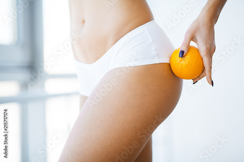 Skin Care Control. Woman Holding an Orange Against Her Thighs