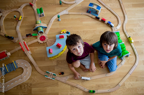 Sweet preschool children, boy brothers, playing with wooden railway and trains at home photo