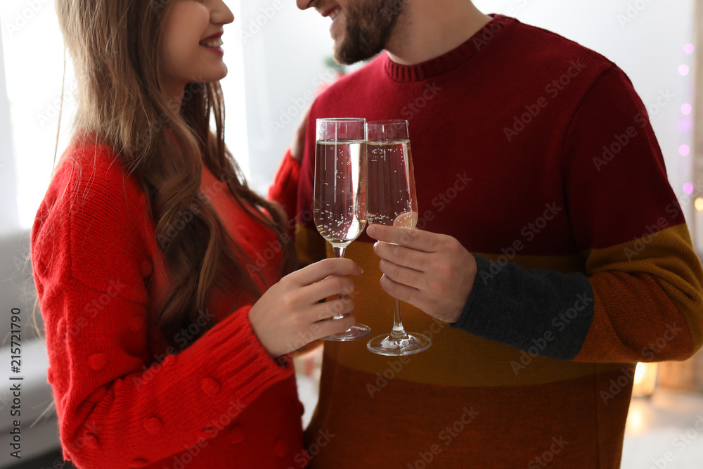 Happy young couple with glasses of champagne celebrating Christmas at home Happy young couple with glasses of champagne celebrating Christmas at home