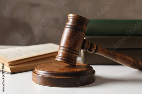 Wooden gavel and books on table against color background, closeup. Law concept