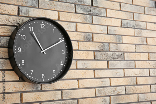 Stylish clock on brick wall. Time concept