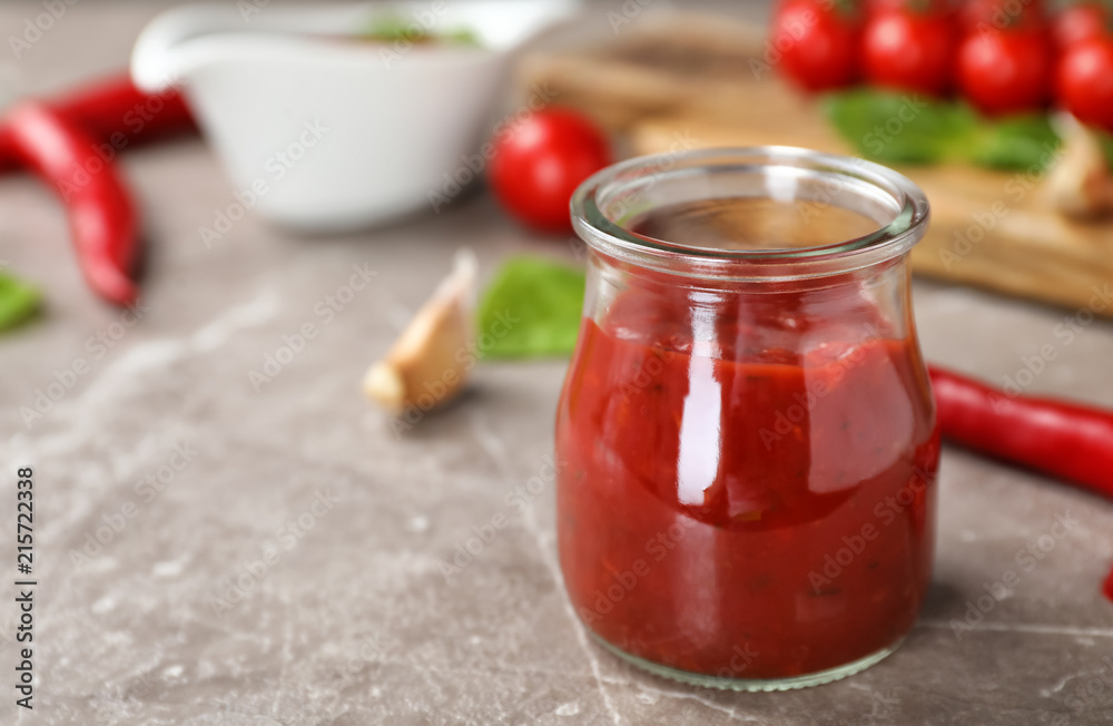 Jar with spicy chili sauce on gray table Jar with spicy chili sauce on gray table
