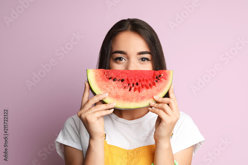Beautiful young woman posing with watermelon on color background