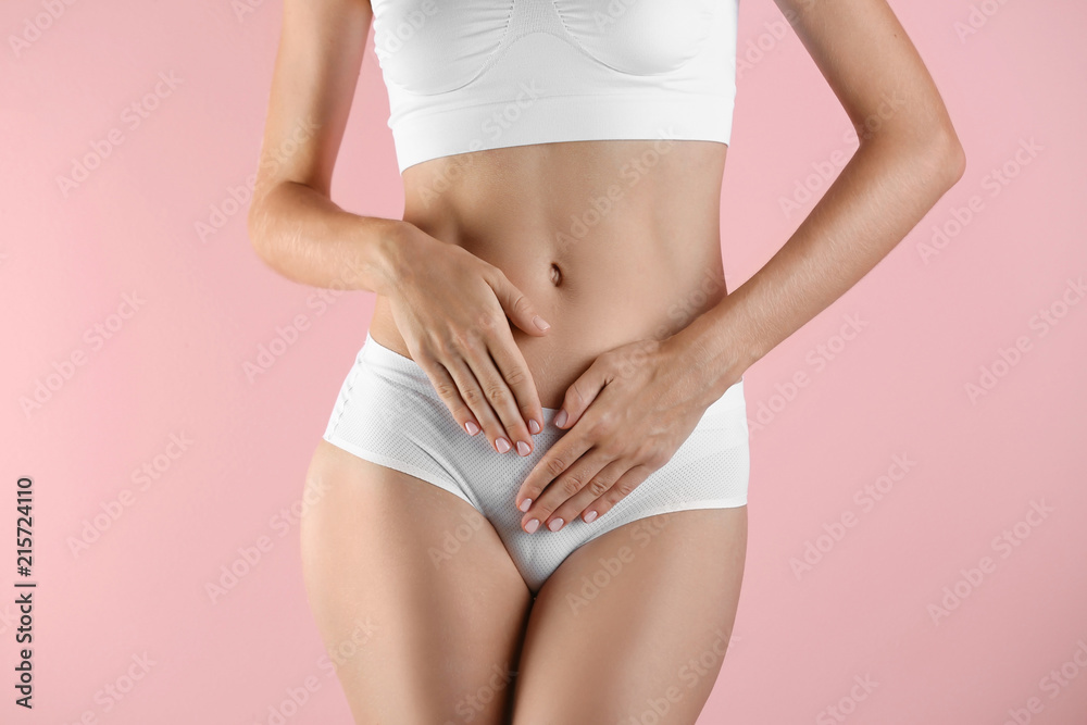 Young woman holding hands near panties on color background. Gynecology concept - obrazy, fototapety, plakaty 