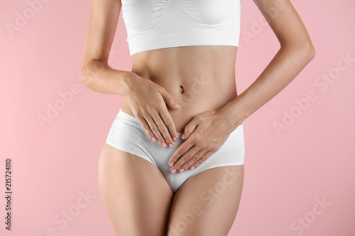 Fototapeta Naklejka Na Ścianę i Meble -  Young woman holding hands near panties on color background. Gynecology concept