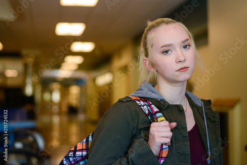 Sad High school student with backpack in school hallway