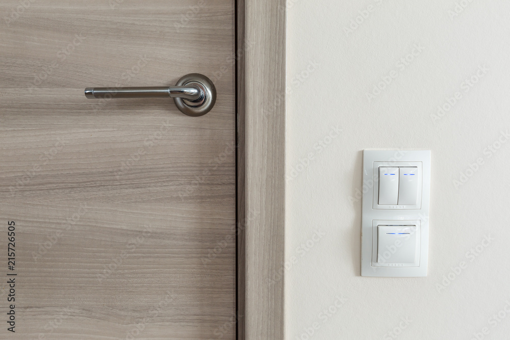 Door handle and white lighting switches on wall Door handle and white lighting switches on wall