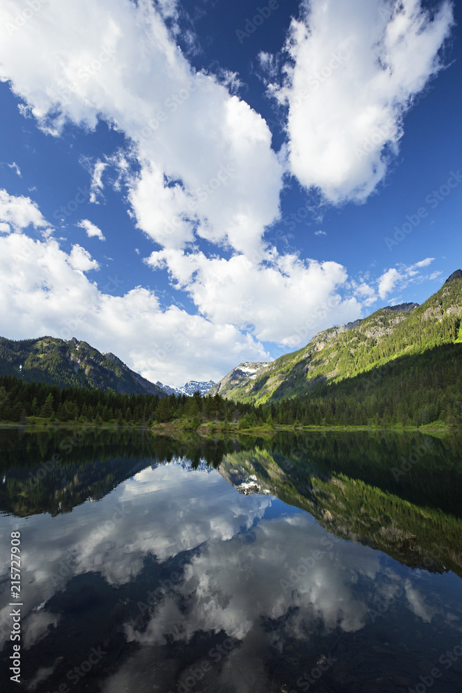 puffy clouds reflected in a mountain pond