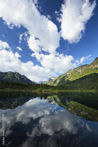 puffy clouds reflected in a mountain pond