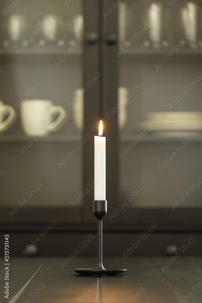 white burning candle in holder over black dining table - vertical white burning candle in holder over black dining table - vertical