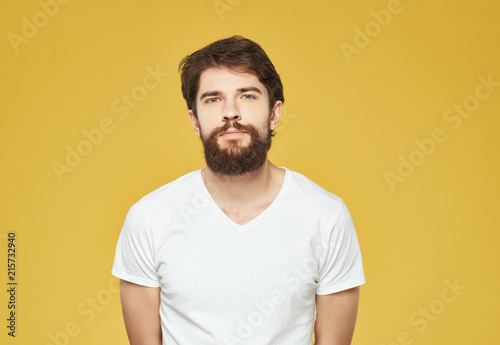man with a beard in a white T-shirt on a yellow background