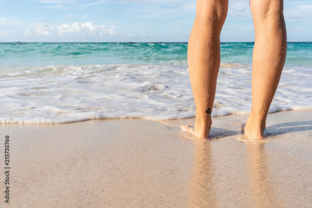 Young woman legs and feet standing on beach Young woman legs and feet standing on beach
