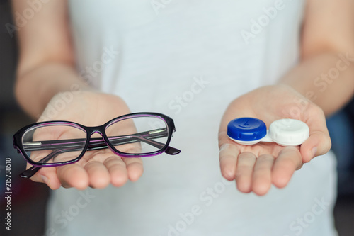 фотографія woman hold contact lenses and glasses in hands
