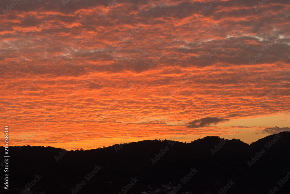 Dusk with orange-coloured clouds by the hills