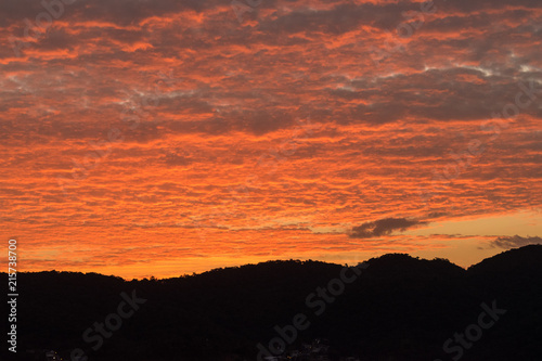 Dusk with orange-coloured clouds by the hills