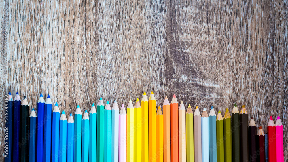 Multi Color pencils in scale with rainbow style isolated on wooden background Multi Color pencils in scale with rainbow style isolated on wooden background