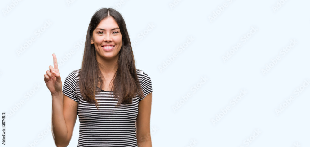 Young beautiful hispanic woman showing and pointing up with finger number one while smiling confident and happy.