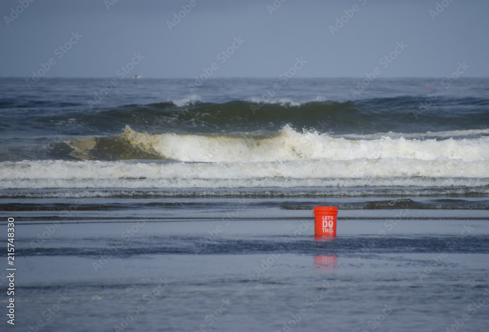 Orange bucket in front of waves Orange bucket in front of waves