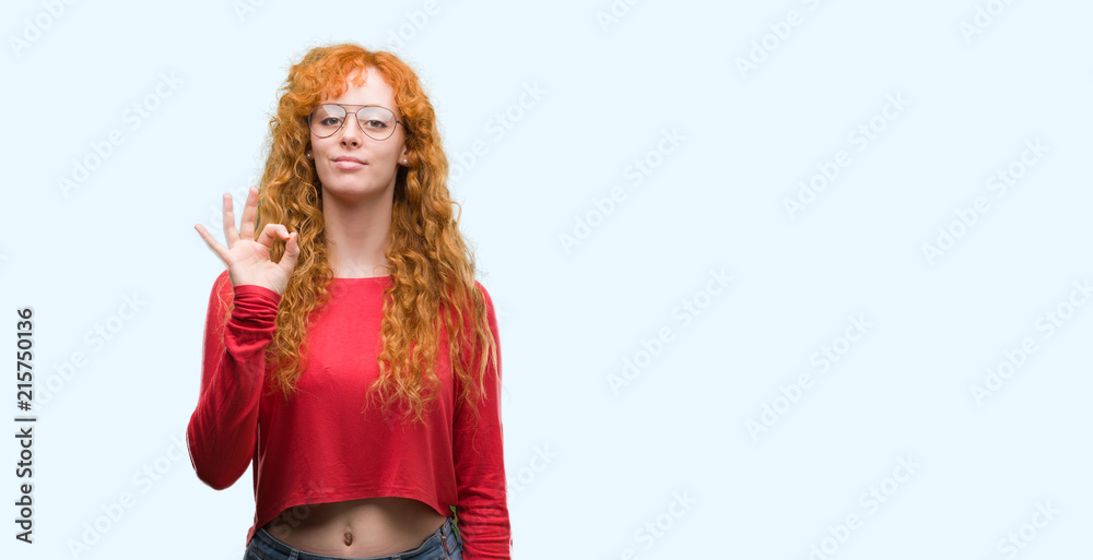 Young redhead woman wearing glasses doing ok sign with fingers, excellent symbol Young redhead woman wearing glasses doing ok sign with fingers, excellent symbol