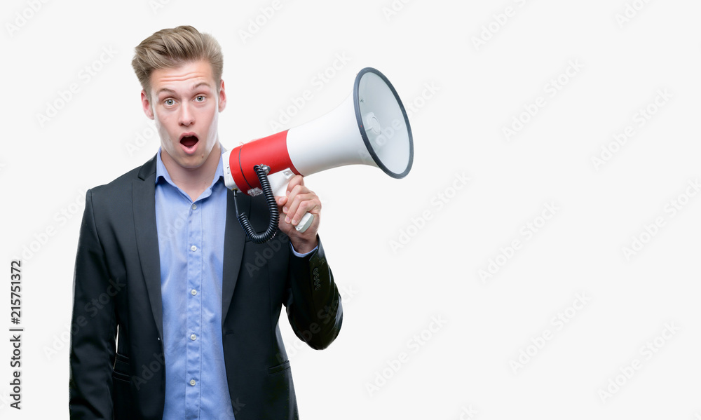 Young handsome blond man holding a megaphone scared in shock with a surprise face, afraid and excited with fear expression Young handsome blond man holding a megaphone scared in shock with a surprise face, afraid and excited with fear expression
