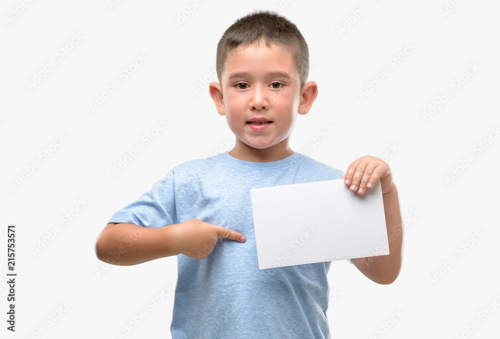 Dark haired little child holding a blank card with surprise face pointing finger to himself Dark haired little child holding a blank card with surprise face pointing finger to himself