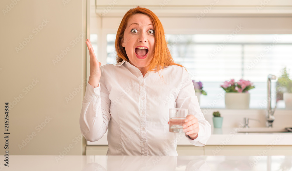 Thirsty redhead woman and glass of water very happy and excited, winner expression celebrating victory screaming with big smile and raised hands Thirsty redhead woman and glass of water very happy and excited, winner expression celebrating victory screaming with big smile and raised hands