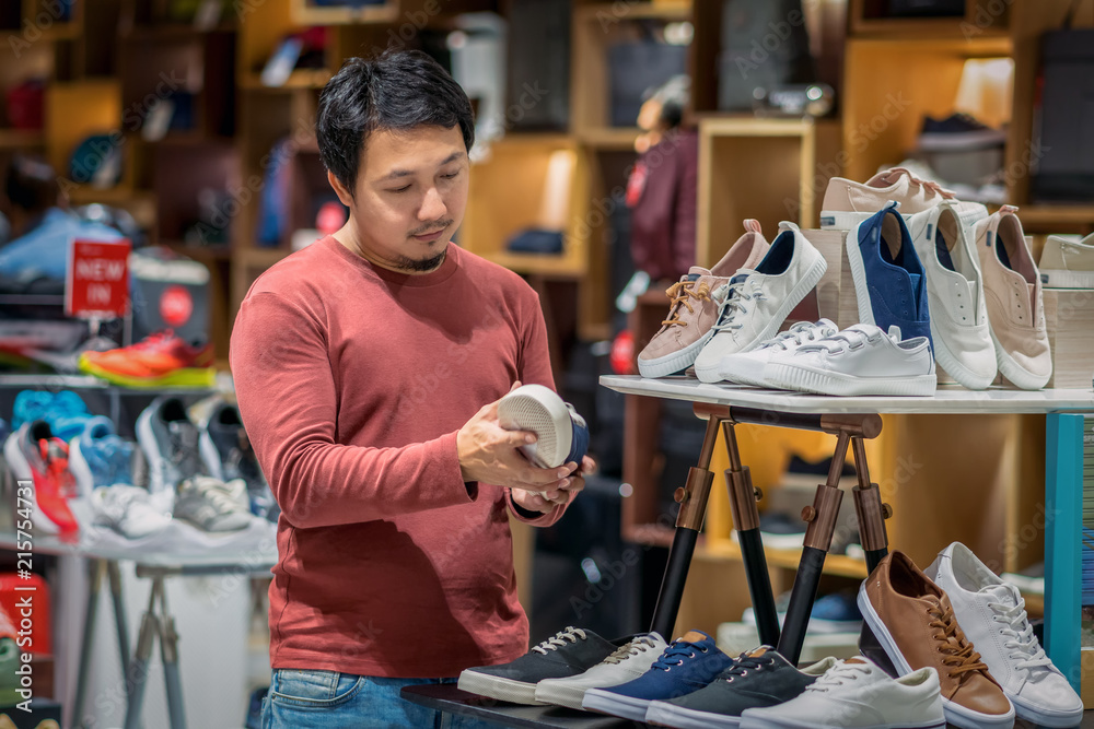 Smart asian man with beard choosing fashion shoes in store shop at department shopping center, beauty and Consumerism Concept.