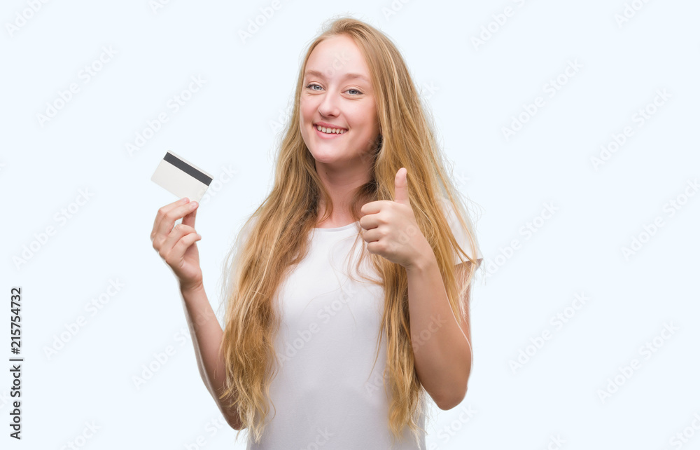 Blonde teenager woman holding credit card happy with big smile doing ok sign, thumb up with fingers, excellent sign Blonde teenager woman holding credit card happy with big smile doing ok sign, thumb up with fingers, excellent sign