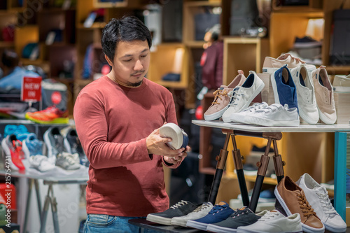 Obraz na płótnie Smart asian man with beard choosing fashion shoes in store shop at department shopping center, beauty and Consumerism Concept. w salonie