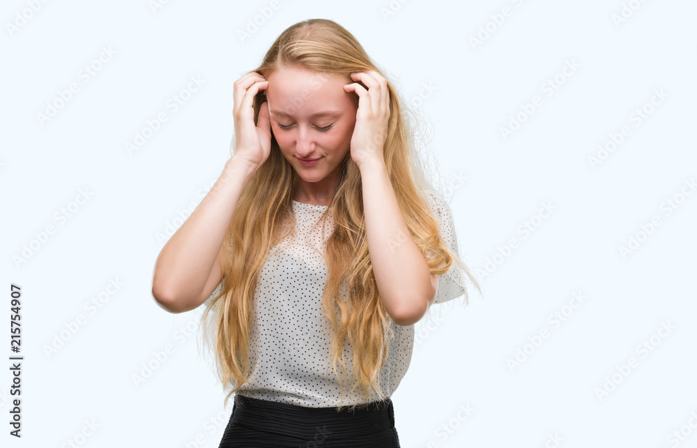 Blonde teenager woman wearing moles shirt with hand on head for pain in head because stress. Suffering migraine.