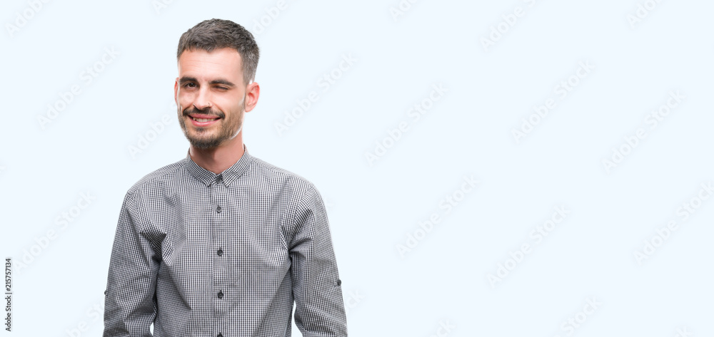 Young hipster man winking looking at the camera with sexy expression, cheerful and happy face. Young hipster man winking looking at the camera with sexy expression, cheerful and happy face.