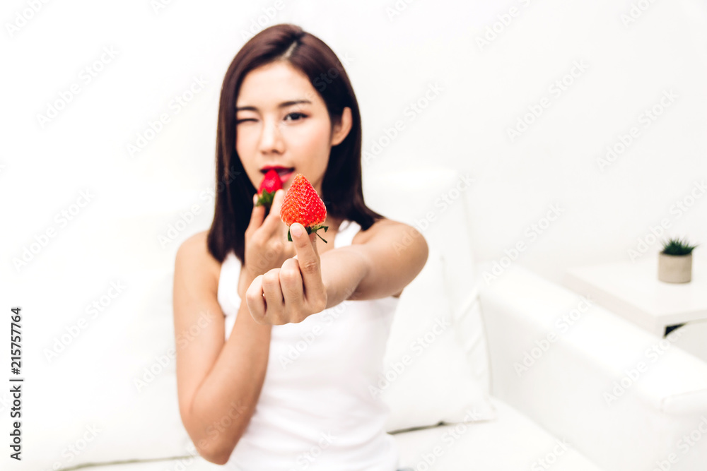 Woman eating fresh strawberry on sofa at home.dieting concept.healthy lifestyle Woman eating fresh strawberry on sofa at home.dieting concept.healthy lifestyle