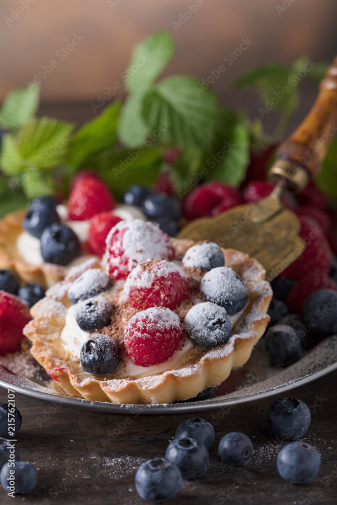 Dessert tarts with raspberries and blueberries on a wooden table. Dessert tarts with raspberries and blueberries on a wooden table.
