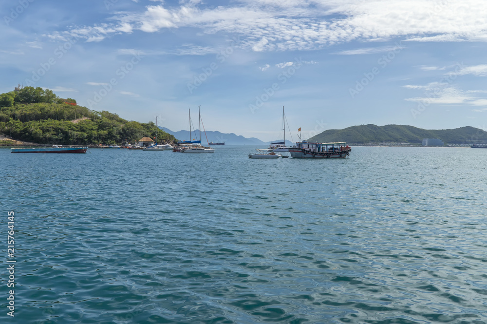 the southern port area, ships and yachts parked in a bay, built in the background on the island of Vinperl, amidst tropical greenery, the blue sky and Nha Trang clouds, Vietnam the southern port area, ships and yachts parked in a bay, built in the background on the island of Vinperl, amidst tropical greenery, the blue sky and Nha Trang clouds, Vietnam