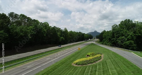 Aerial view of cars commuting with Pilot Mountain's peak in the distance.