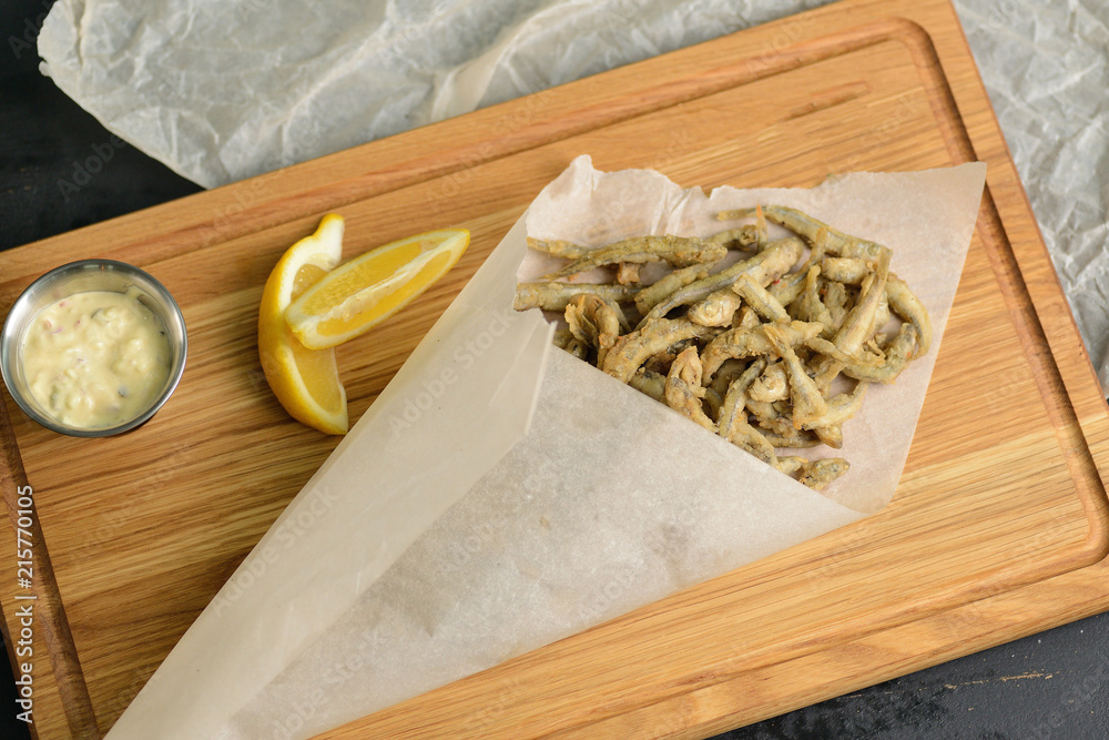 fried fish in a paper bag on a wooden board