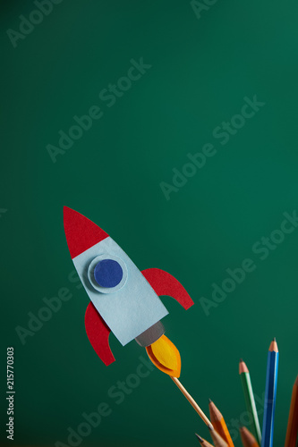 pencils and colorful rocket with green chalkboard on background