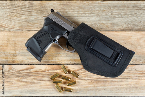 pistol with ammunition and holster on a wood background