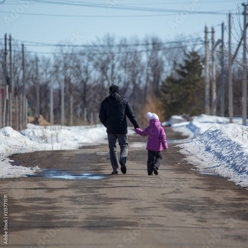 Girl with dad walking on the road in winter