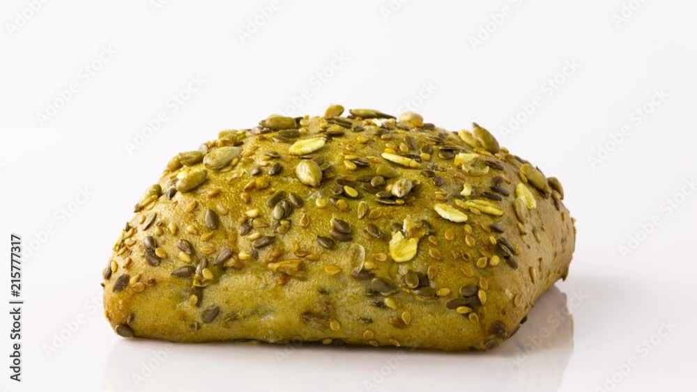 Rotating wholemeal bread roll on turntable on white background Rotating wholemeal bread roll on turntable on white background