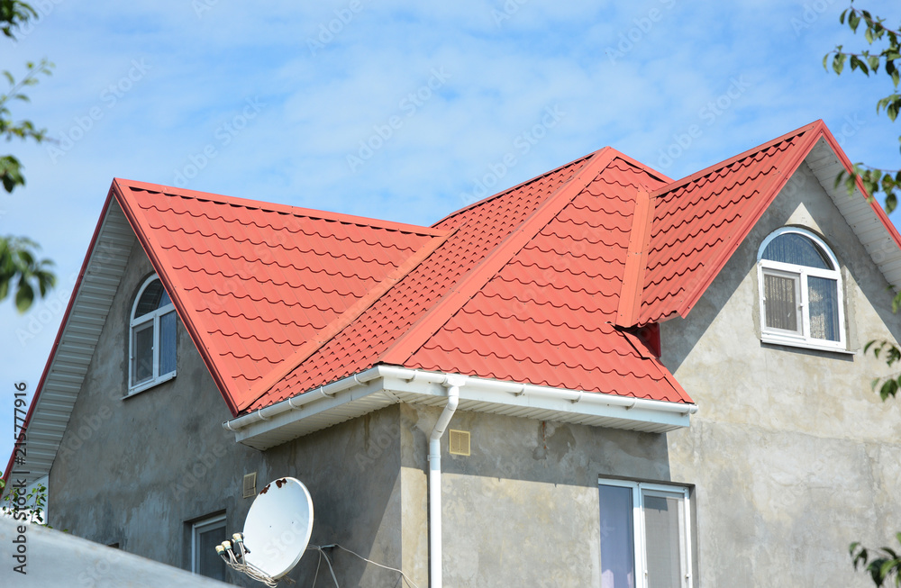 Roofing construction with attic windows,  rain gutter waterproofing. Guttering down pipe fittings. Roof gutter system on house metal tiles roofing.