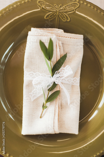 Green decorated cutlery with plant leaves and white napkins on wedding table. Rustic style