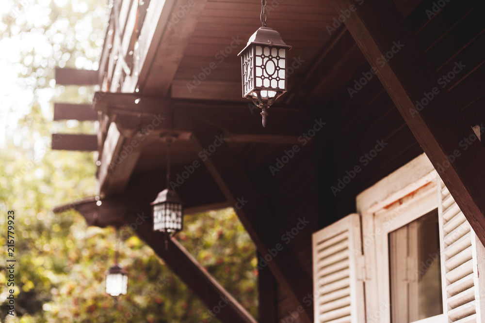 Old forged lantern hanging on terrace of wooden house