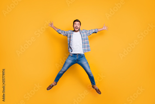 Full-legh portrait of of crazy and excited handsome man jumping up like a star isolated on shine yellow background