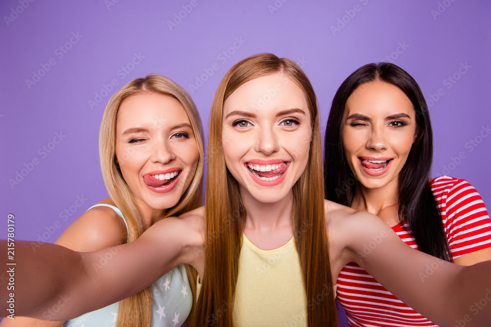 Self portrait of funky cool girls gesturing tongue out winking with one eye enjoying weekend together isolated on bright violet background. Rest relax leisure concept Self portrait of funky cool girls gesturing tongue out winking with one eye enjoying weekend together isolated on bright violet background. Rest relax leisure concept