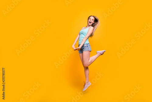 Full-body portrait of gorgeous blond model jump high and rejoice isolated on vivid yellow background with copyspace for text © deagreez