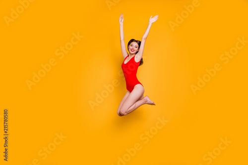 Freedom restless concept. Full-size portrait of excited girl with rise up hands jumping up isolated on yellow background