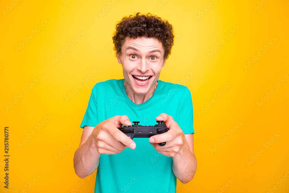 Young attractive handsome cheerful guy wearing casual green polo t-shirt enjoying playing video game. Isolated over vivid shine bright yellow background Young attractive handsome cheerful guy wearing casual green polo t-shirt enjoying playing video game. Isolated over vivid shine bright yellow background