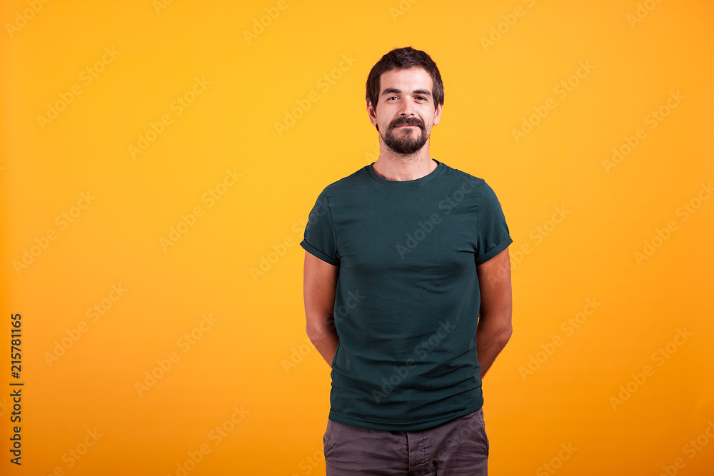 Handsome smiling man with arms at his back on orange background in studio. Portrait of happy cheerful fashionable guy looking at the camera Handsome smiling man with arms at his back on orange background in studio. Portrait of happy cheerful fashionable guy looking at the camera